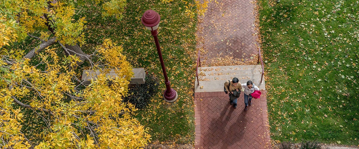 drone view of two people walking on campus