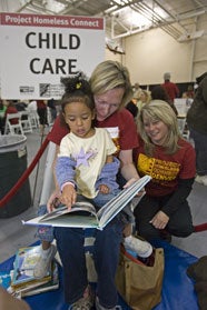 Project Homeless Connect volunteer reading to child