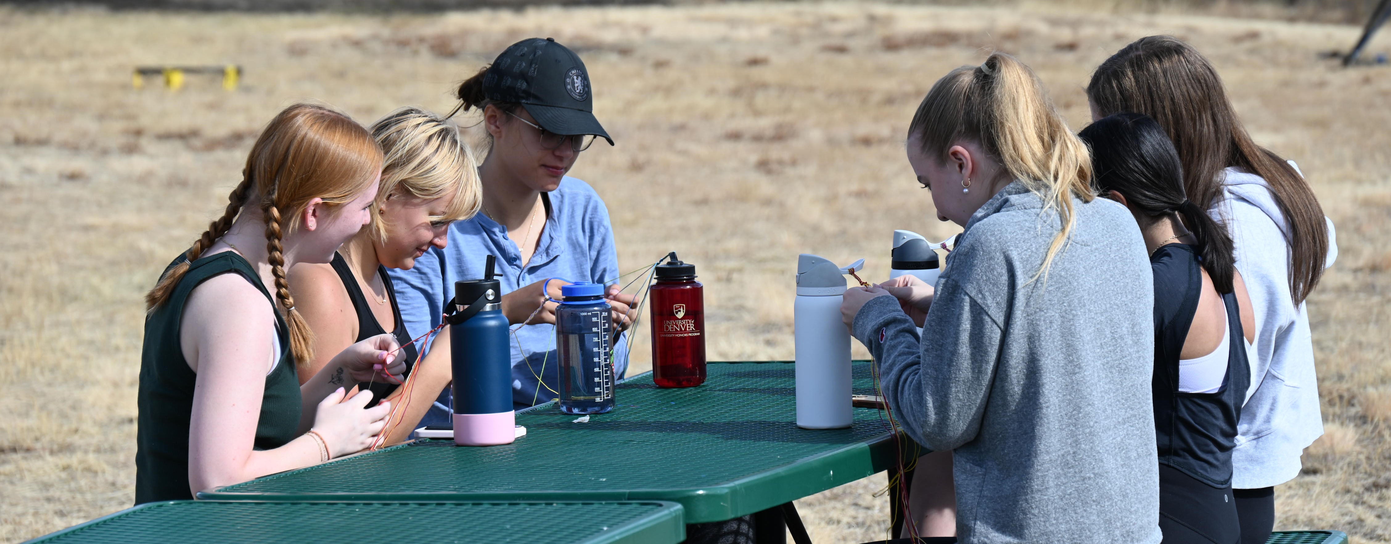 students gathered at picnic table in the meadow
