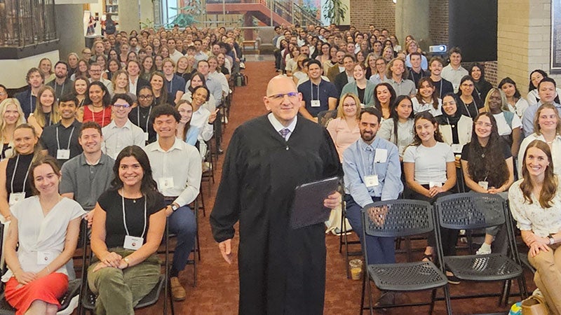Justice Carlos Samour standing center and incoming students, seated