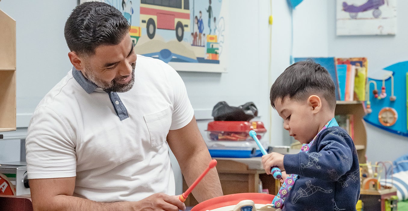 a person is playing a drum with a kid