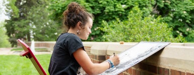 a student is drawing on a board on campus