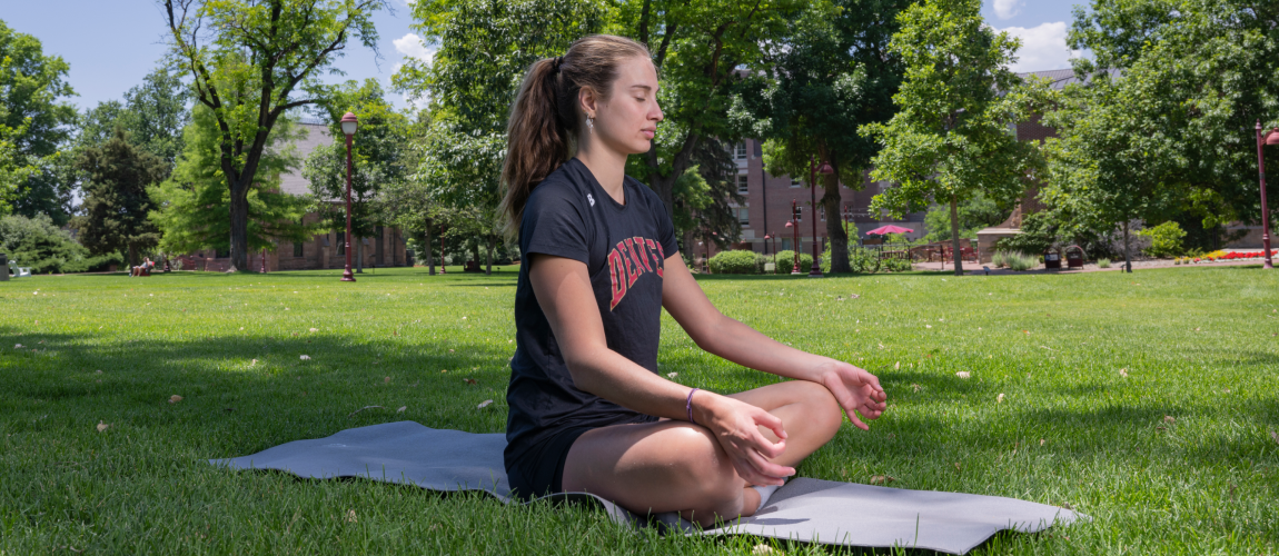 A student doing yoga on the lawn