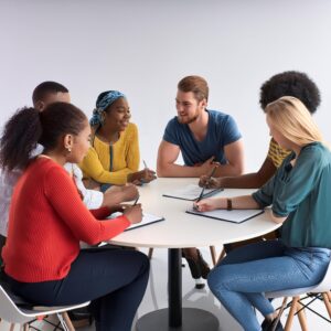 diverse group of students meet together at a round table with notes