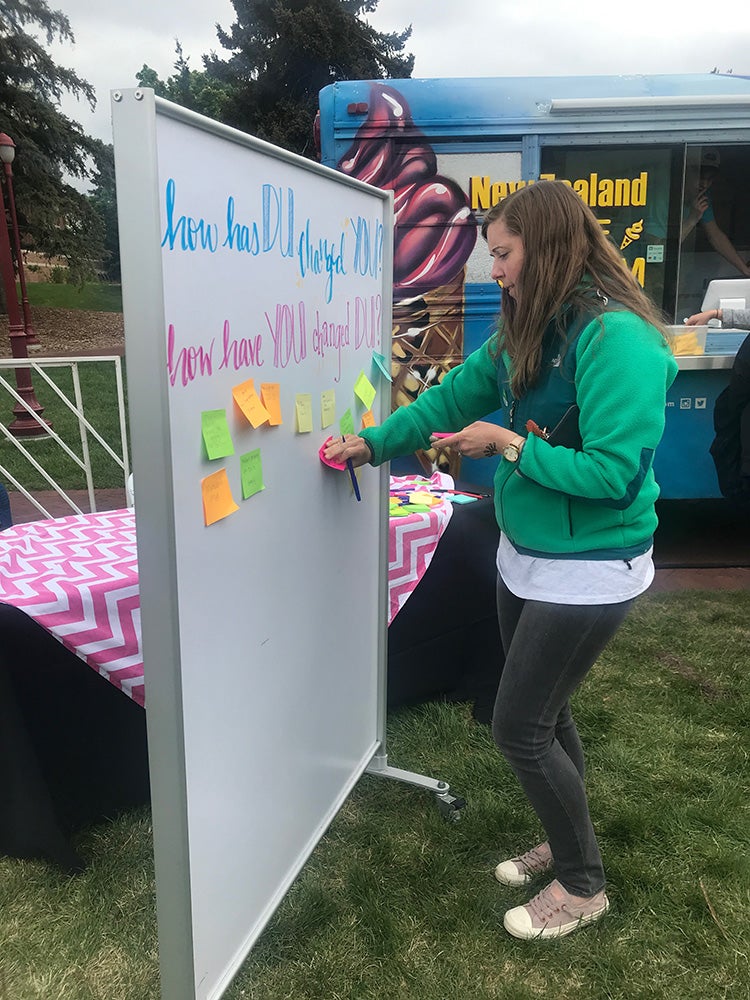 Woman adding post-it notes to DU message board.