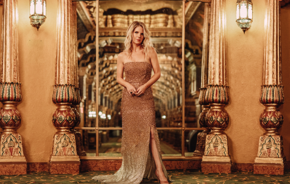 Broadway singer Kelli O'Hara wears a gold dress in an ornate theater lobby.