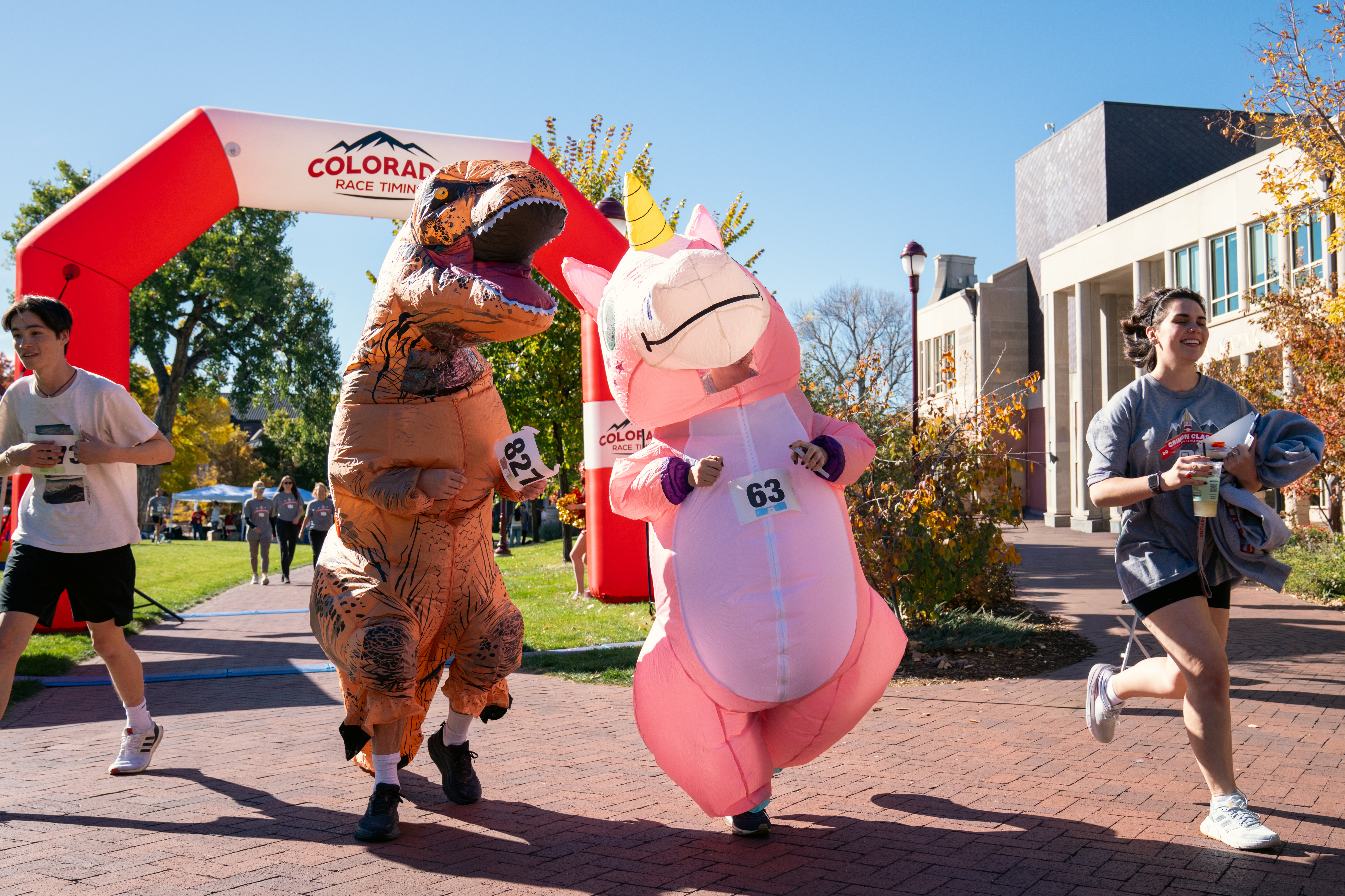 people dressing in dinosaur and unicorn costume running crimson classic 5K