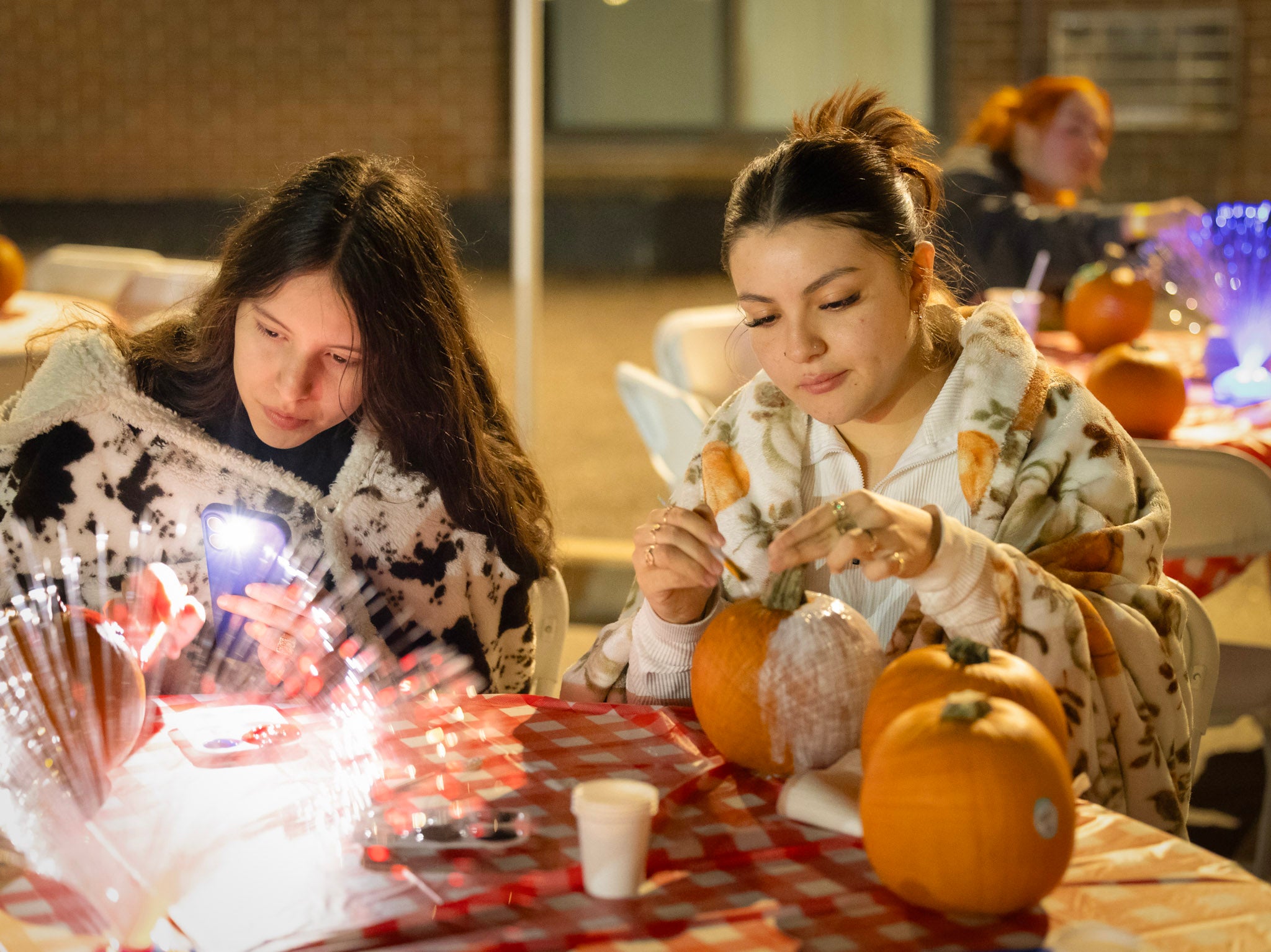 two students painting pumpkins