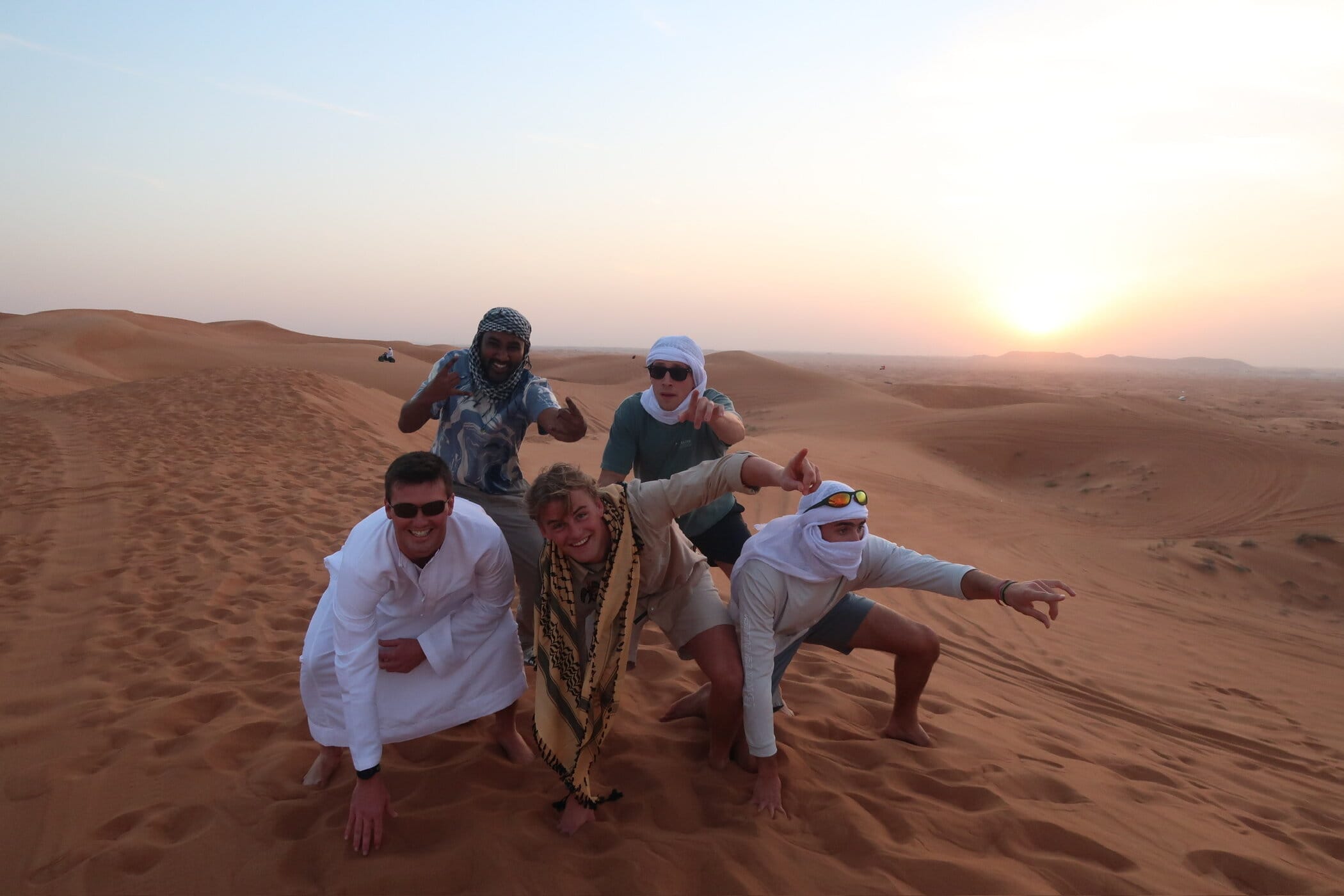Students pose for a group photo on a sand dune during a travel course by the Daniels College of Business.