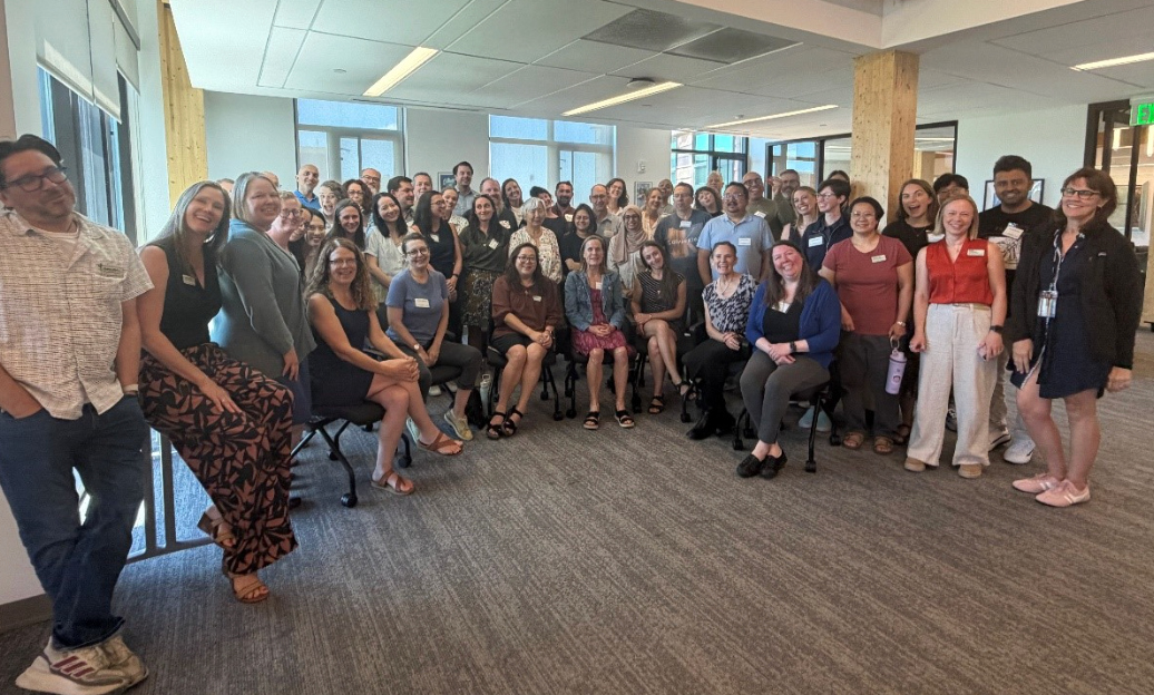 c27c9cb0-2573-46b2-8349-fc2a5ee3ef05.png Group of people smiling in a room