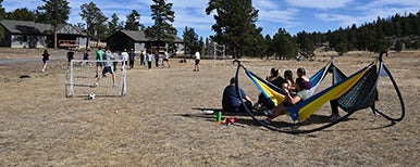 students playing soccer while others recline in hammocks and watch