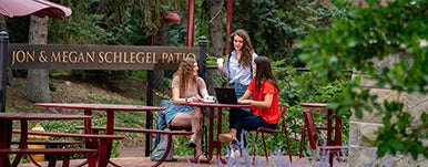 three students seated at picnic table