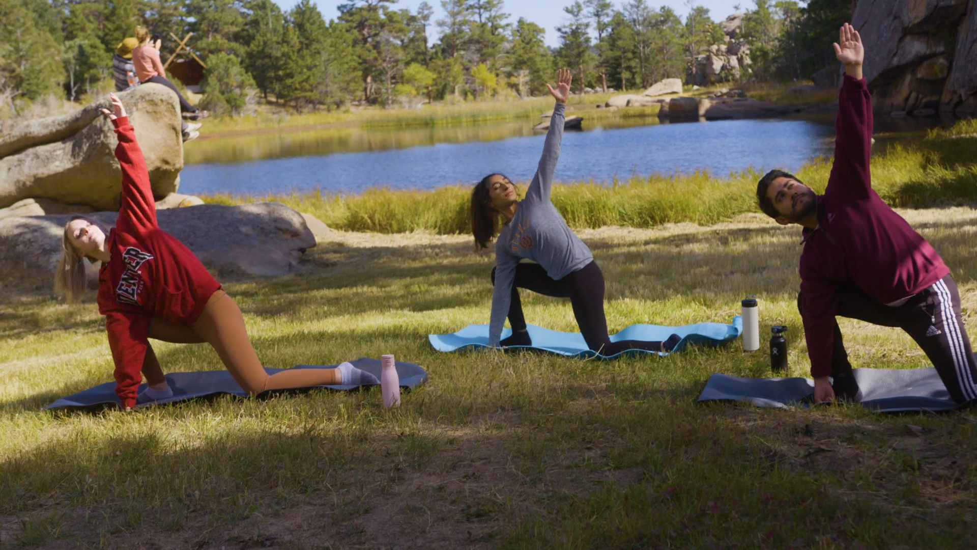 three students doing yoga in meadow