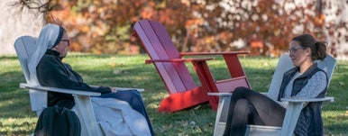 students sitting and talking on adirondack chairs