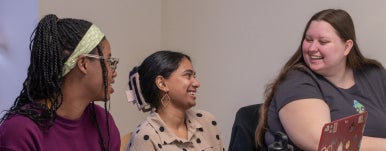 3 students smiling at one another