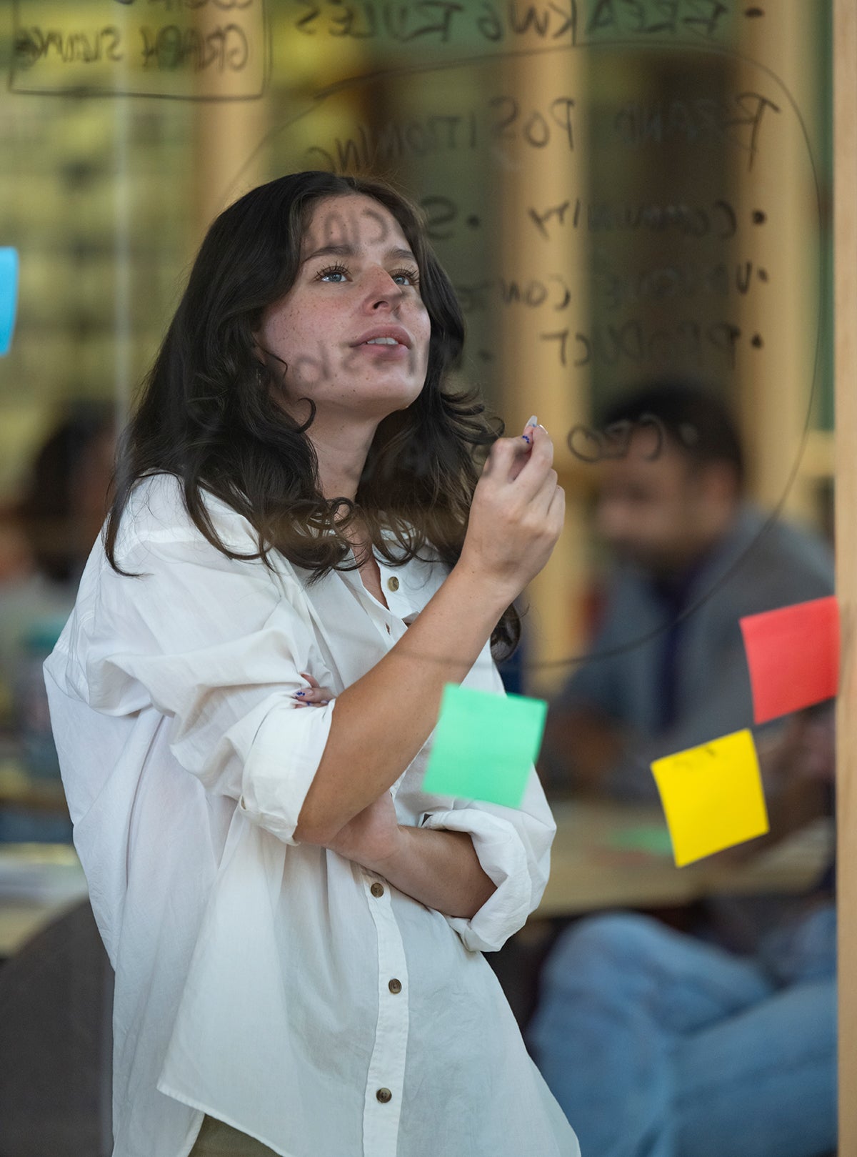 a person looking at the writing and stickers on glass board