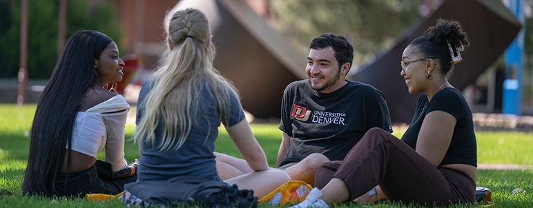 four students sitting on a lawn