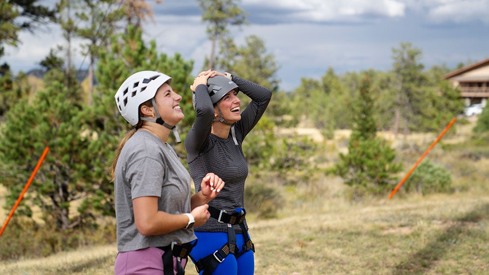 two students wearing climbing gear look up