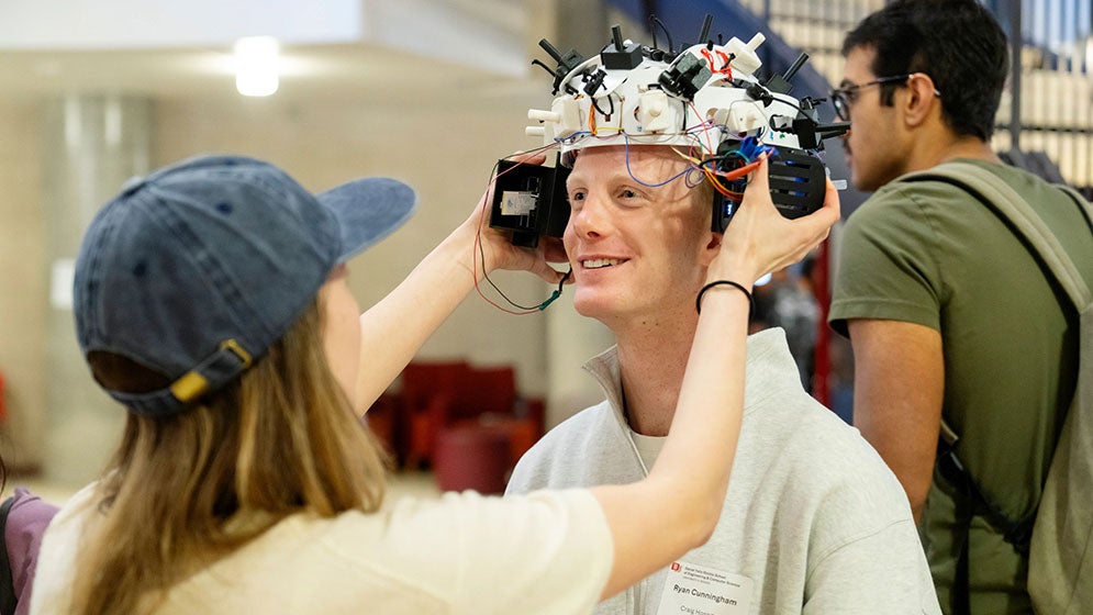 a person tries on a head device at Senior Design Symposium