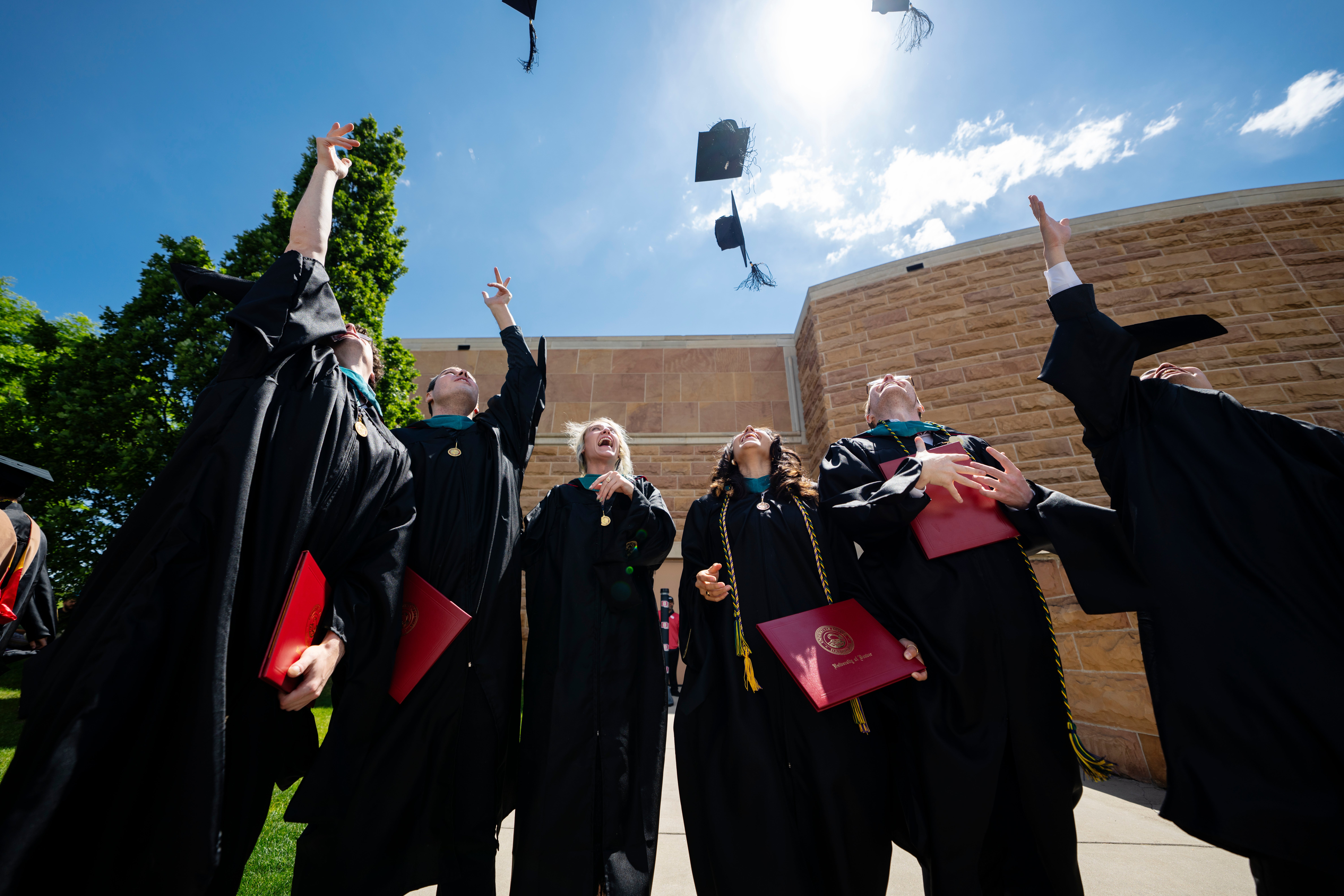 graduates throwing their hats in the air outside