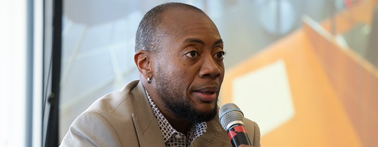 a person speaking with a microphone on stage of spark event