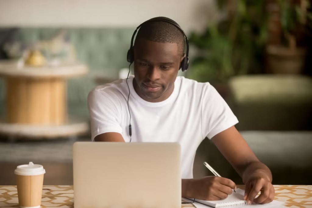 a person looking at his laptop and taking note
