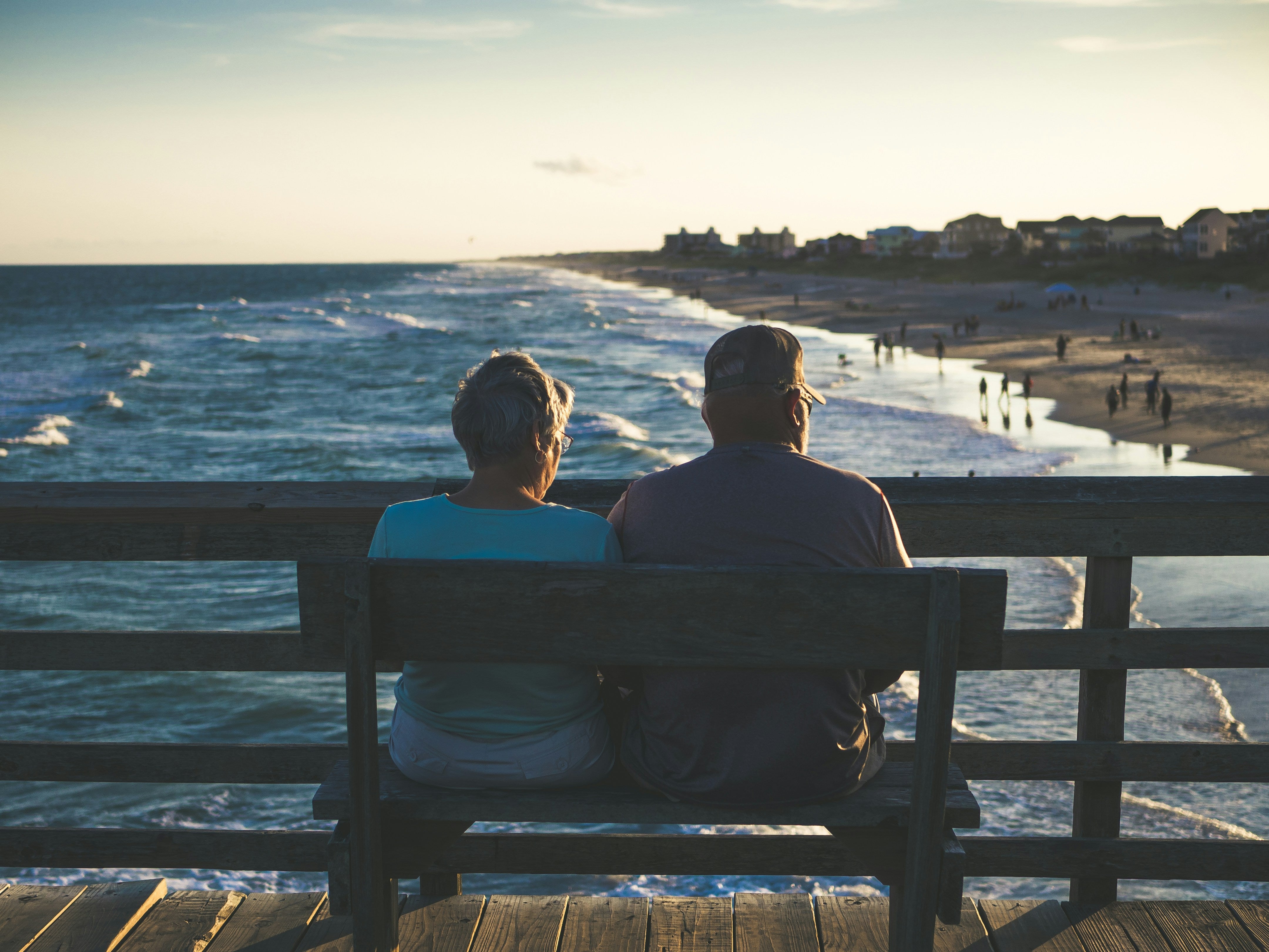 Two people sitting on a bench overlooking the ocean.