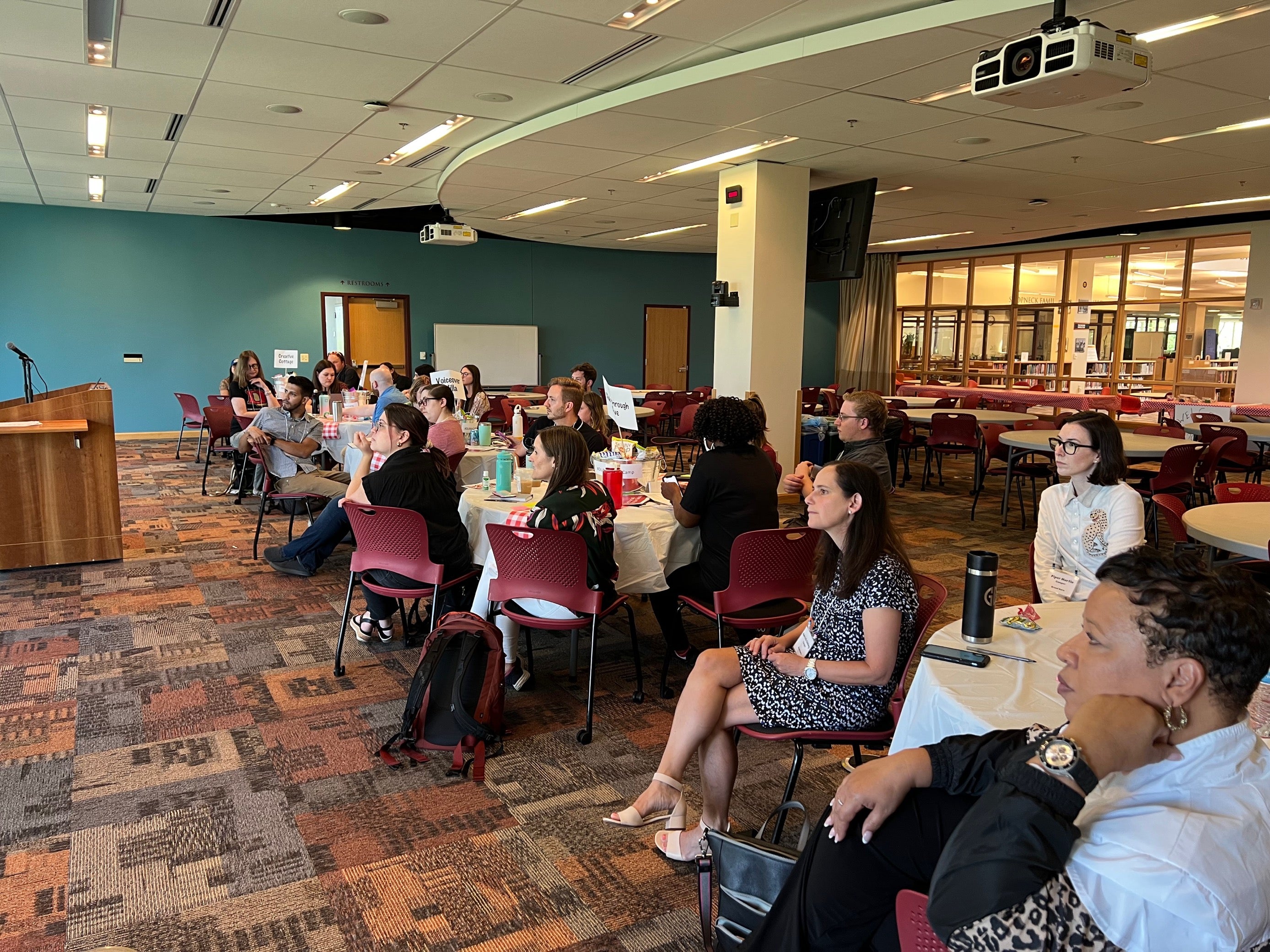 people sitting at tables listening to someone speaking