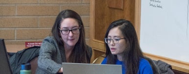 two people work on a laptop