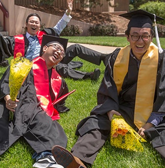 students sitting on the lawn celebrating graduation