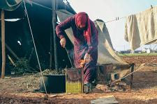 A woman in a Syrian Refugee camp cooks a meal