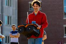 Alumnus and graduate student Ori Miller, carrying a robot that the ARISE lab uses in its research