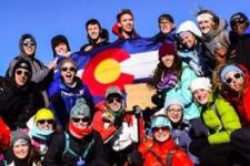 Students atop mountain with Colorado flag