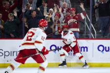 DU hockey players celebrate with fans behind the glass