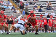 A DU lacrosse player in a face off with a Syracuse lacrosse player.