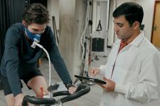 A student conducts physiology research with an athlete using a bicycle