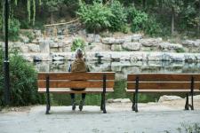 Man sitting on a bench looking at a stream