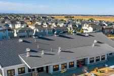 exterior of STEAD school, a white barn like structure with houses in the background 