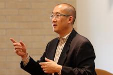 Bernard Chao with arms extended, speaking