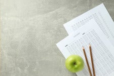 exams, pencils and apple arranged on table