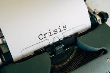 an old printer printing a paper that says 'crisis'