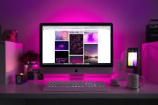 a stylish desk with Mac computer and pink backlighting