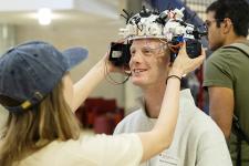 A student placing an EEG device on another student's head
