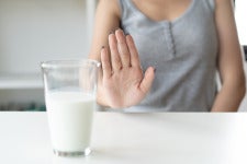 hand signals no to glass of milk on counter
