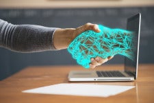 a digital hand reaches out from laptop screen to computer user