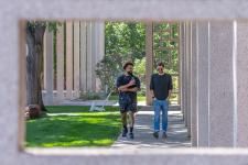 Two male students walk along a campus path.