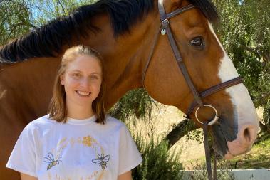 A student standing next to her horse.