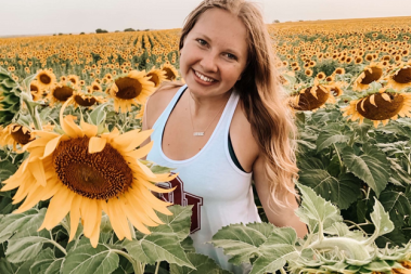student posing with sunflowers