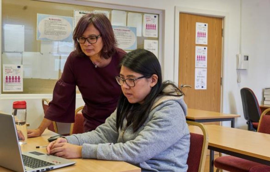 Student and teaching looking at a laptop, working together.