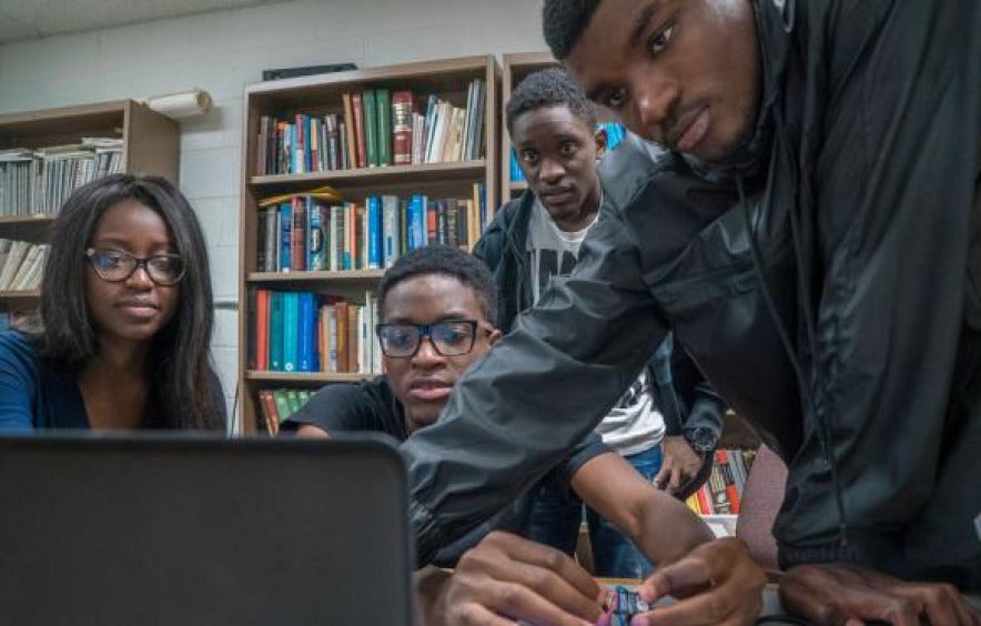 group of african american students work together looking toward shared computer screen